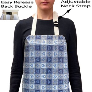 May include: An apron featuring a blue and white geometric design. It has an adjustable neck strap and an easy-release back buckle. The apron is made of a durable fabric, suitable for kitchen or craft activities.