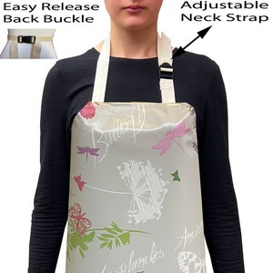 May include: A grey waterproof apron with a floral pattern featuring butterflies, dragonflies, and birds. The apron has an adjustable neck strap and an easy release back buckle.