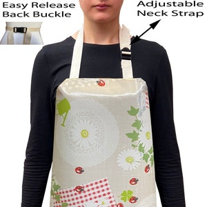 May include: A beige apron with a floral and ladybug print. The apron has an adjustable neck strap and an easy release back buckle.