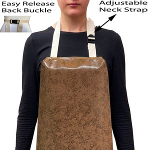 May include: A brown leather-look apron with adjustable neck straps and an easy release back buckle. The apron is being worn by a person standing in front of a white background.