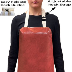 May include: A rust-coloured waterproof apron with adjustable neck straps and an easy release back buckle. The apron is being worn by a person wearing blue jeans.