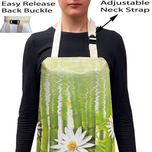May include: Apron featuring a green bamboo and white flower design. It has an adjustable neck strap and an easy-release back buckle. The apron is made of a durable material, suitable for cooking and other kitchen tasks.