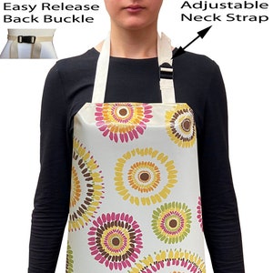 May include: A white apron with an adjustable neck strap and an easy release back buckle. The apron has a colourful pattern of pink, yellow, orange, and brown circles.