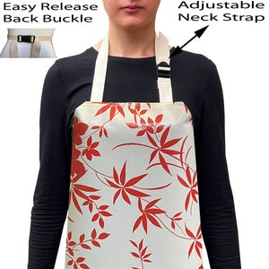 May include: A white apron with a red floral pattern. The apron has adjustable neck straps and an easy release back buckle.