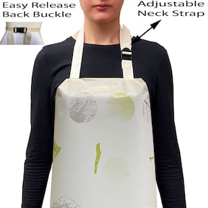 May include: A white apron with a leaf pattern and a light green background. The apron has an adjustable neck strap and an easy release back buckle.