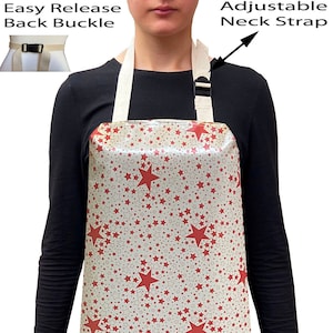 May include: A white apron with a red star pattern. The apron has an adjustable neck strap and an easy release back buckle.