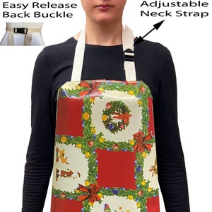 May include: A red and white Christmas-themed apron with a chequered pattern. The apron has a white adjustable neck strap with a black buckle and an easy release back buckle. The apron features a variety of Christmas images, including wreaths, baubles, a Christmas tree, and Father Christmas.