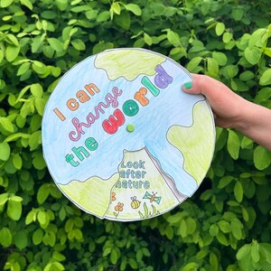 Könnte beinhalten: Handgezeichnete, runde Illustration der Erde mit dem Text "I can change the world" in verschiedenen Farben. Die Worte "Look after nature" sind ebenfalls enthalten, zusammen mit Zeichnungen von Blumen, Bienen und Schmetterlingen.