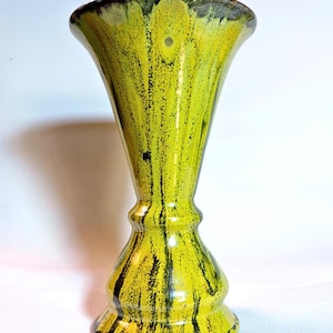 Può includere: Un vaso in ceramica giallo con striature nere e marroni. Il vaso ha un'ampia apertura e una base stretta.