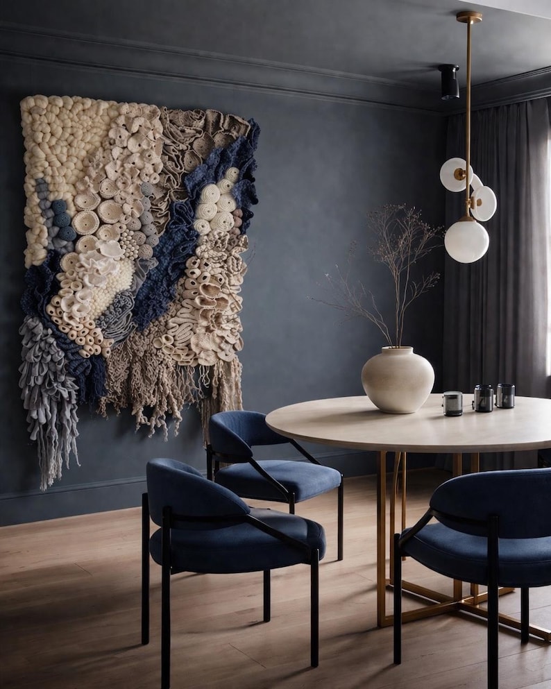Puede incluir: Un comedor moderno con un tapiz de pared texturizado en tonos crema, azul y beige. La habitaci&oacute;n incluye una mesa redonda, sillas azules y una l&aacute;mpara decorativa, creando un espacio elegante y acogedor.