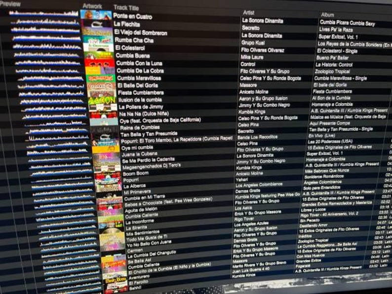May include: A computer screen displays a music library with a list of songs, artists, and albums. The interface shows album art and track titles, with a focus on Latin music genres like Cumbia. The screen is angled.