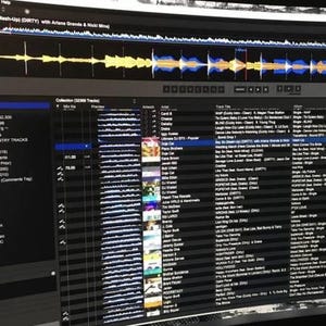Può includere: Uno schermo di computer che mostra un'interfaccia software per DJ. Lo schermo mostra forme d'onda, playlist e informazioni sui brani. Il software include brani musicali e playlist, tra cui "HOT DANCE COUNTRY TRACKS" e "SLOW JAMS 2020".