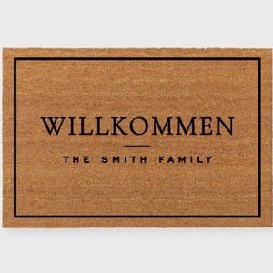 May include: A brown coir doormat with a black border and the text "WILLKOMMEN THE SMITH FAMILY" in black.
