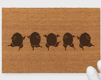 May include: A brown coir doormat with a line of five brown turkeys walking across the mat. The turkeys are facing the right side of the mat.