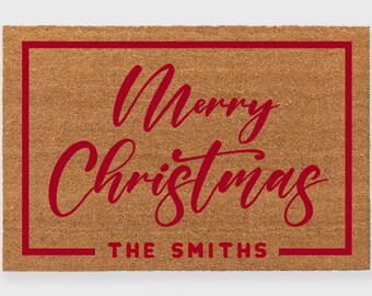 May include: A brown coir doormat with a red border and the text "Merry Christmas" in red cursive lettering. The text "THE SMITHS" is also in red lettering below the main text.