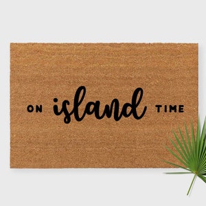 May include: A brown coir doormat with the text "ON island TIME" in black lettering.