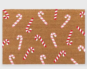 May include: A brown coir doormat with a repeating pattern of red and pink candy canes.