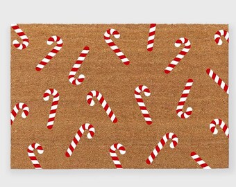May include: A brown doormat with a red and white candy cane pattern. The candy canes are scattered across the doormat in a random pattern.