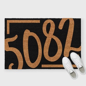 May include: A black doormat with a gold border and the number "5082" written in a large, stylized font.