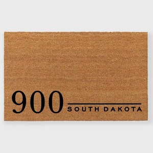 May include: A brown coir doormat with the number "900" and the text "SOUTH DAKOTA" printed in black.