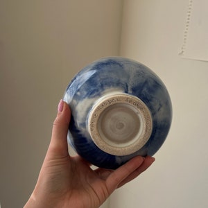 May include: A blue and white ceramic bowl with a white glaze. The bottom of the bowl has a handwritten inscription that reads "SZ GLAZ 14/11/BGZ".