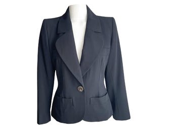May include: A dark navy blazer with a single-button closure and two front pockets. The blazer is displayed on a white mannequin, showcasing its tailored fit and classic design. The lapels are notched, and the sleeves are long.