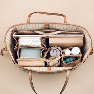 May include: A brown and tan patterned tote bag with a zippered top and multiple compartments. The bag is filled with various items, including a laptop, a water bottle, a small container, and a few other items.