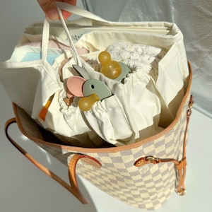 Könnte beinhalten: Ein Set aus drei Keramikbechern mit gesprenkelter, cremefarbener Glasur. Jeder Becher zeigt ein handgemaltes Blumendesign in Blau-, Grün- und Gelbtönen. Die Becher haben eine einfache, abgerundete Form und einen bequemen Griff.