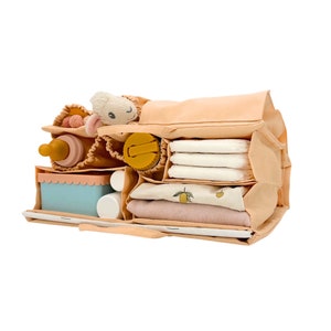 May include: A beige diaper bag organizer with multiple compartments. The organizer is filled with various baby items, including a stuffed animal, bottles, wipes, and a change of clothes.