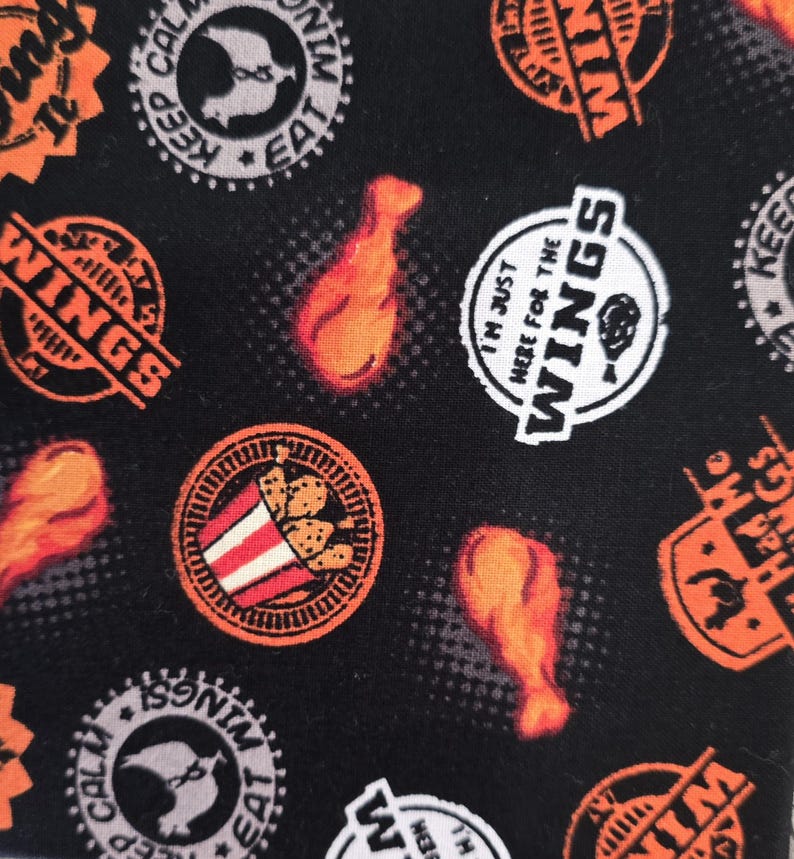 May include: A black fabric featuring a repeating pattern of orange chicken drumsticks and circular badges. The badges contain text including "Keep Calm and Eat Wings," "I'm Just Here for the Wings," and "Had Me at Wings," along with chicken illustrations.