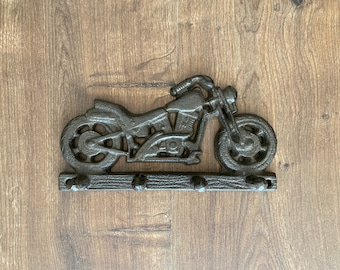 Könnte beinhalten: Ein schwarzer Schlüsselhalter aus Gusseisen in Form eines Motorrads mit drei Haken. Das Motorrad ist in Seitenansicht.