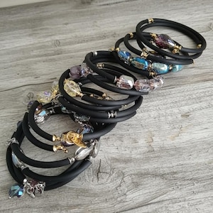 Mehrlagiges, gewickeltes Armband aus schwarzem Memory-Draht mit Glasperlen. Gummischlauch, Edelstahl- und vergoldete Verschlüsse.