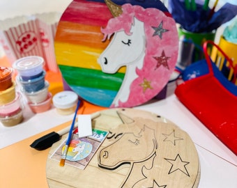 May include: A unicorn craft kit with two wooden circles, one painted with a rainbow and a unicorn, the other blank. The kit includes paint, brushes, and a small card with a unicorn illustration.