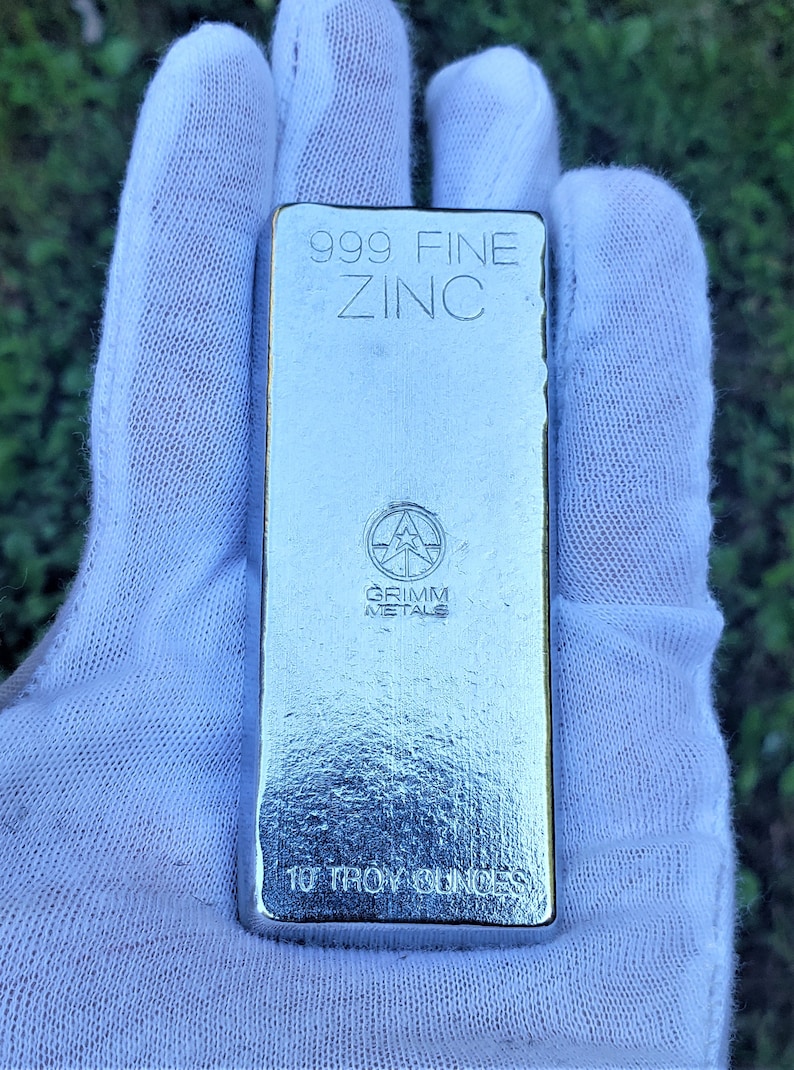 May include: A silver bar of 999 fine zinc, weighing 10 troy ounces. The bar is stamped with the words "999 FINE ZINC" and "GRIMM METALS".