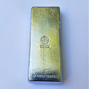 May include: A silver bar of 999 fine zinc, weighing 10 troy ounces. The bar is stamped with the Grimm Metale logo and the words "999 Fine Zinc" and "10 Troy Ounces".