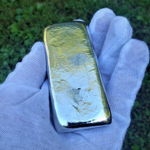 May include: A silver bar with a textured surface. The bar is rectangular and has a shiny, metallic finish.