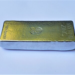 May include: A silver bar of zinc with the text "99.9 FINE ZINC" and "10 TROY OUNCES" on the side.