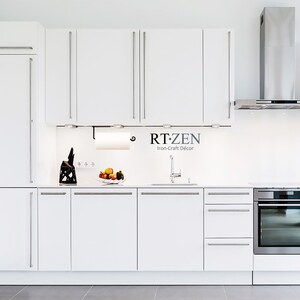Pode incluir: Uma cozinha branca com eletrodom&eacute;sticos de a&ccedil;o inoxid&aacute;vel, arm&aacute;rios brancos e um exaustor de a&ccedil;o inoxid&aacute;vel. A cozinha tem uma bancada branca com uma pia e uma torneira de a&ccedil;o inoxid&aacute;vel. H&aacute; uma fruteira na bancada com ma&ccedil;&atilde;s e laranjas. O texto "RT:ZEN Iron-Craft Decor" &eacute; vis&iacute;vel no protetor de parede.