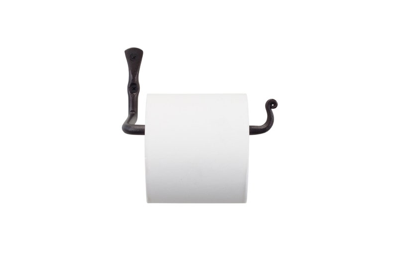 May include: Black metal toilet roll holder with a curved arm and a decorative scroll design. The holder is mounted to a wall and has a white toilet roll on it.