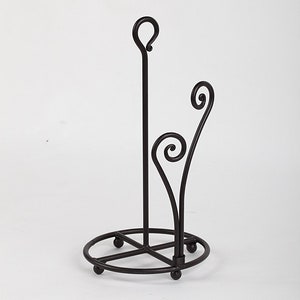 May include: A black metal paper towel holder with a decorative scroll design. The holder has a round base and a vertical rod with a loop at the top.