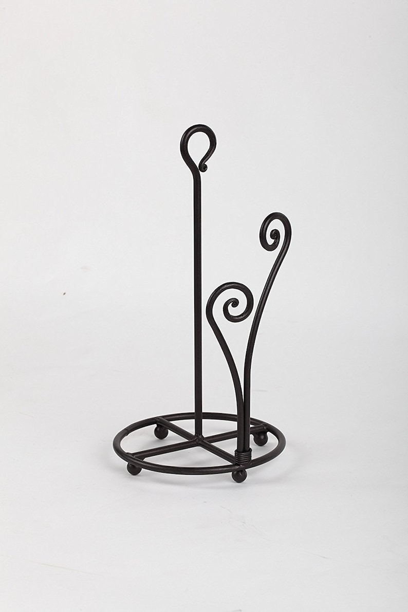 May include: A black metal paper towel holder with a decorative scroll design. The holder has a round base and a vertical rod with a loop at the top.