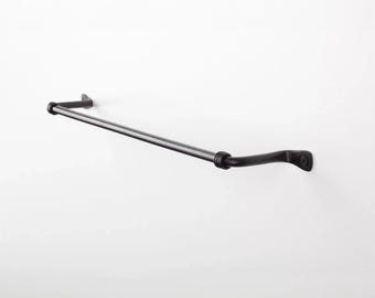 May include: Black metal curtain rod with rounded finials and wall brackets. The rod is curved at one end.