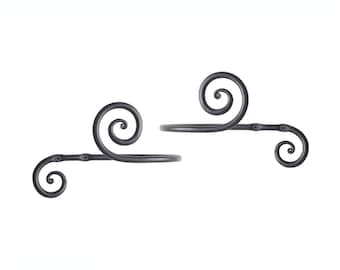 May include: Two black metal curtain holdbacks with a decorative scroll design. Each holdback has a small round knob on the side.