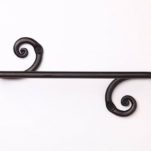 May include: Black metal towel rack with decorative scrollwork on the ends.