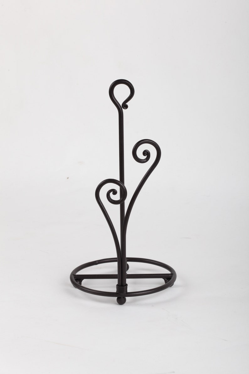 May include: Black metal paper towel holder with a round base and a decorative swirl design.