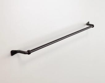 May include: Black metal towel bar with curved ends. The bar is mounted to a white wall.