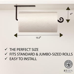 May include: Black metal paper towel holder with a decorative scroll design. It is mounted under a cabinet and holds a standard or jumbo-sized roll of paper towels. The holder measures 13.2 inches wide and 4 inches high.