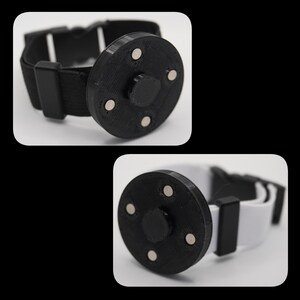 Puede incluir: Una pulsera negra con un disco magnético redondo negro. El disco tiene cuatro imanes plateados en el borde exterior.