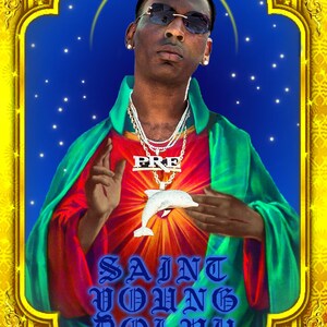 May include: A digital art print of a man wearing sunglasses and a green and red robe with a gold chain necklace. The necklace has a pendant with the word "PRE" on it. The man is holding a white dolphin in his hands. The background is blue with white stars. The text "SAINT YOUNG DOLPH" is written in blue letters at the bottom of the image.