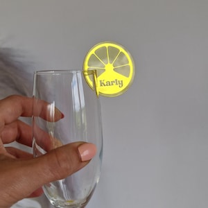 May include: Yellow lemon-shaped glass drink marker with the name "Karly" printed on it.